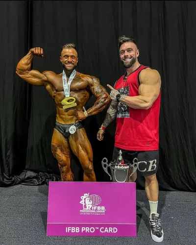 Darren Farrell's client Nikita with his IFBB Pro card