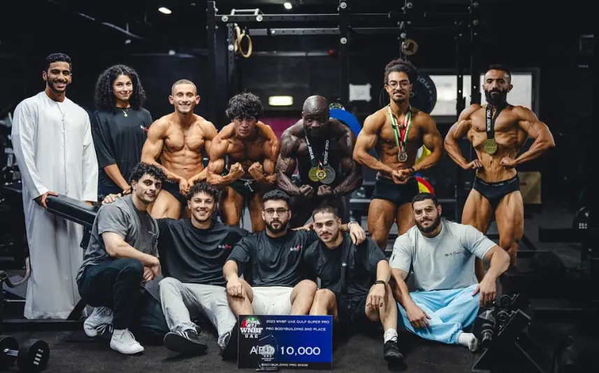 The team in the gym with medals and the prize board
